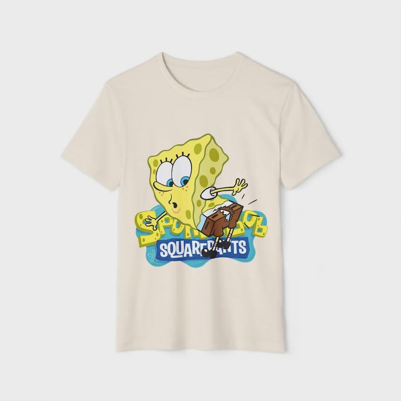 Op de afbeelding: Cr&egrave;mekleurig T-shirt met een cartoonafbeelding van SpongeBob SquarePants. Het gele personage wordt afgebeeld met een verbaasde uitdrukking, naast de woorden "SQUAREPANTS" in een blauw en geel ontwerp.