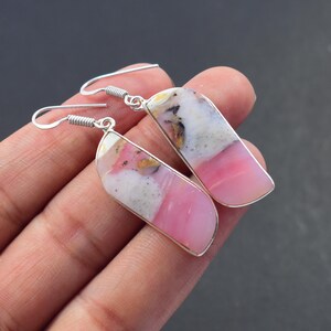 Op de afbeelding: Een paar oorbellen met een rechthoekige vorm, met een combinatie van roze, witte en grijze stenen. De stenen zijn gezet in een zilverkleurig metalen frame en de oorbellen hebben een haaksluiting.