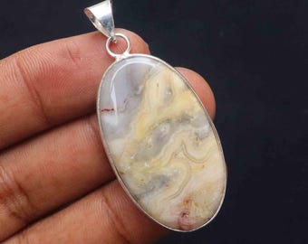 May include: A silver pendant featuring a white, yellow, and brown agate stone with a swirling pattern. The stone is oval-shaped and set in a silver frame.