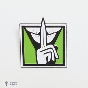 May include: A black and white enamel pin with a green background. The pin features a hand holding a knife to its mouth, with a smiling mouth shape around the knife. The text "Shhh" is written in a black font.