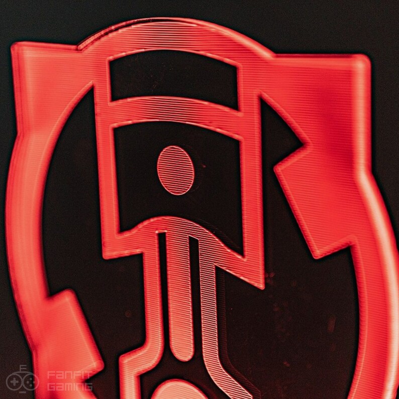 May include: A red 3D printed logo with a piston design. The piston is outlined in black and has a red circle in the center. The logo is surrounded by a red circle.