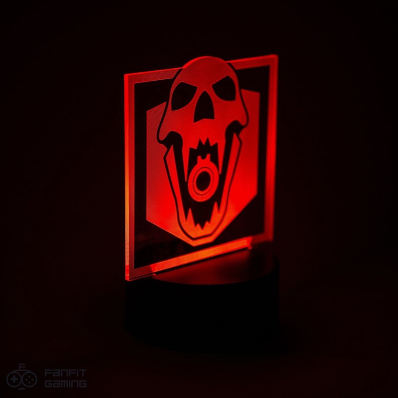 May include: A red illuminated acrylic light with a black skull design. The skull has a large open mouth with a gear inside. The light is on a black base.