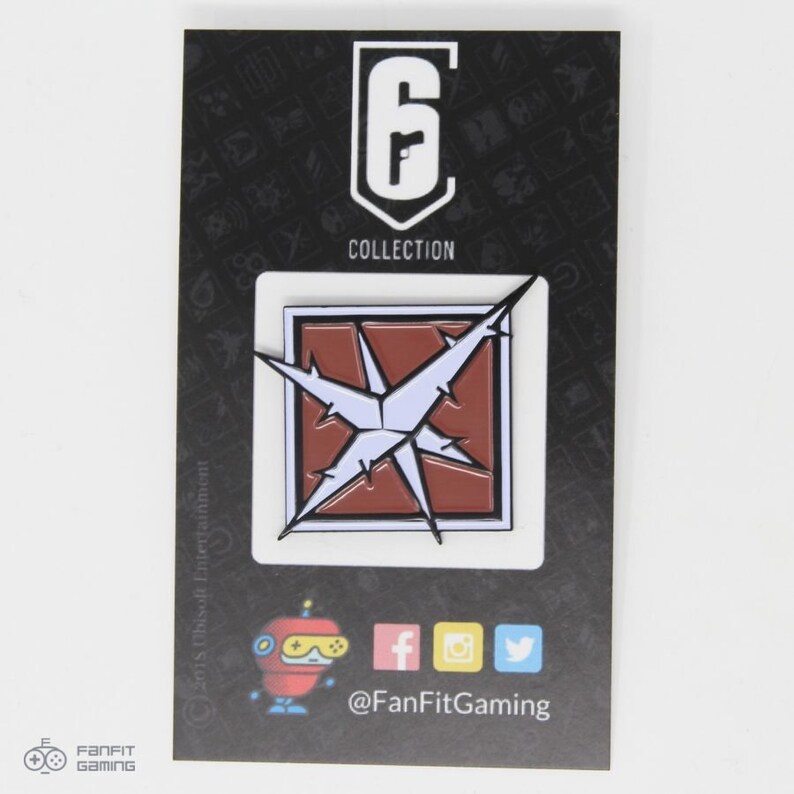 May include: A black and white enamel pin featuring the Rainbow Six Siege logo and a red and white symbol with a starburst design. The pin is on a black card with the text "Collection" and "@FanFitGaming".