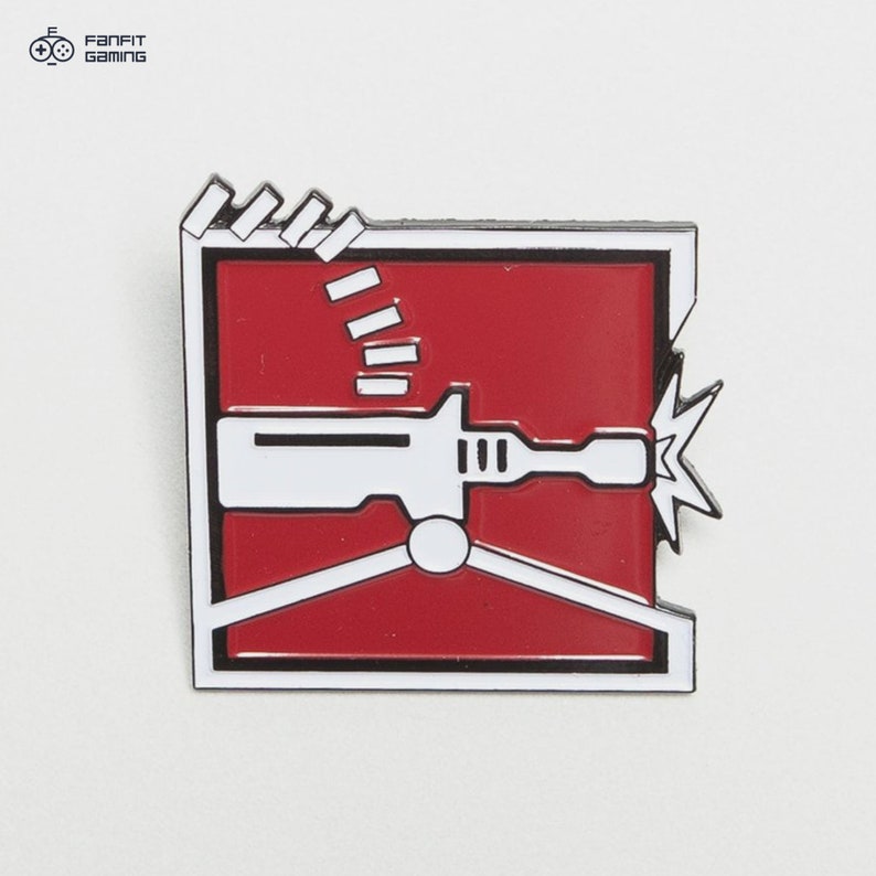 May include: A red and white enamel pin featuring a stylized image of a machine gun with a red background and a white outline. The pin is shaped like a square with rounded corners.