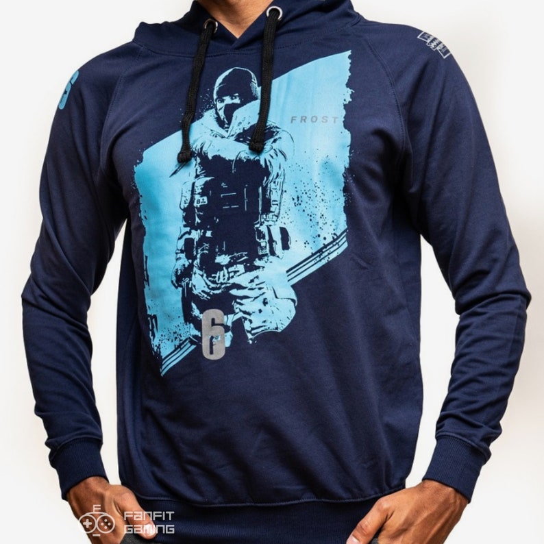 May include: A navy blue hooded sweatshirt with a graphic print of a video game character holding a weapon. The character is wearing a black mask and is standing in front of a blue and white background. The text "FROST" and the number "6" are also printed on the sweatshirt.