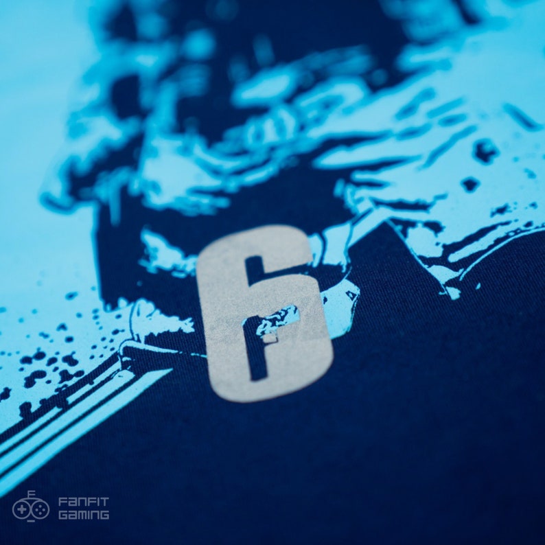 May include: A navy blue t-shirt with a light blue graphic of a person and the number "6" in a silver color.