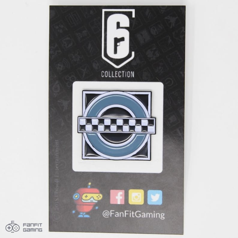 May include: A black and white enamel pin featuring a checkered pattern and a blue circle with a white outline. The pin is on a black card with the text "Rainbow Six Collection" and a logo for the game.