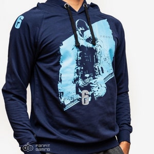 May include: A navy blue hooded sweatshirt with a graphic print of a video game character holding a gun. The character is in front of a blue and white background. The text "Frost" and "6" are printed on the sweatshirt.