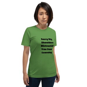 May include: A green t-shirt with the text "Sorry My Shoulders Distracted You from Learning" printed in black.