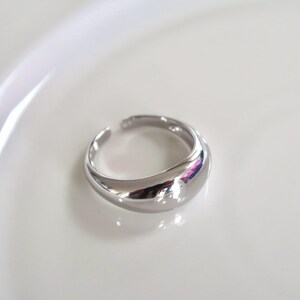 May include: A silver ring with a smooth, rounded, and slightly domed top.