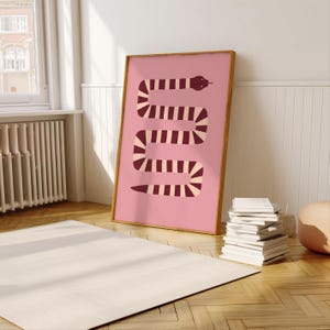 May include: A pink framed poster featuring a burgundy and cream striped snake design. The snake is curled in a vertical S shape.