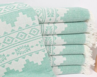 May include: A stack of six mint green Turkish towels with white geometric patterns. The towels have fringe edges and are folded neatly.