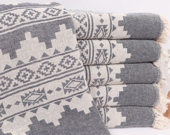 Peut inclure: Une pile de serviettes turques à franges, à motifs gris et blancs. Les serviettes ont un motif géométrique et sont pliées soigneusement.