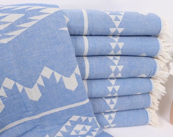 May include: A stack of light blue Turkish towels with a white geometric pattern. The towels have a white fringe on the edges.
