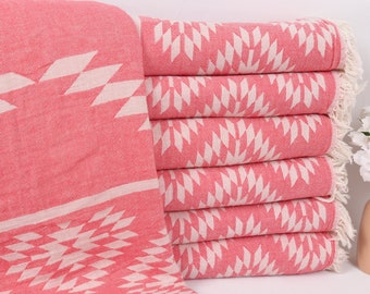 Puede incluir: Una pila de toallas turcas de color rosa y blanco con bordes con flecos. Las toallas están dobladas y apiladas sobre una superficie blanca.