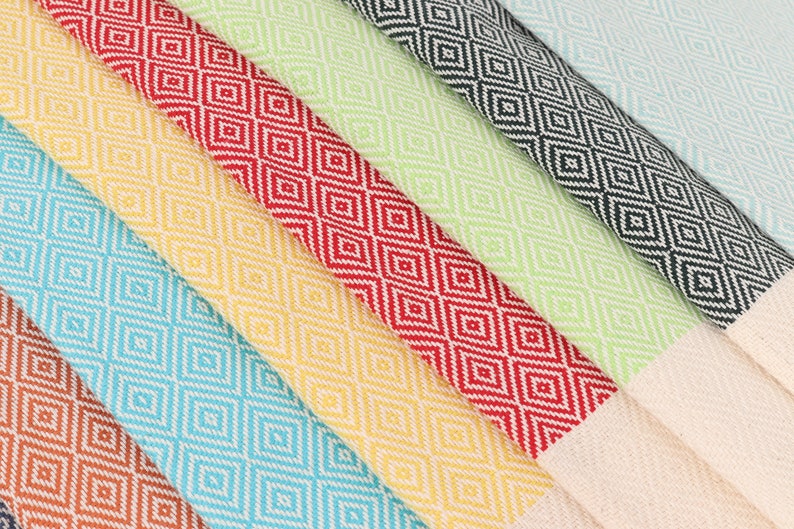 May include: A set of six Turkish towels in various colours, including turquoise, yellow, red, green, and black. The towels feature a diamond pattern and are made of cotton.