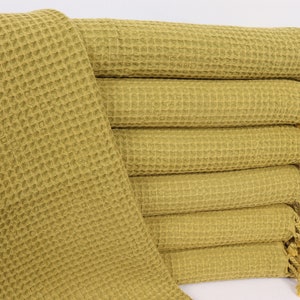 以下が含まれることがあります： フリンジ付きのワッフル織りのオリーブグリーンのタオルが8枚重ねられています。