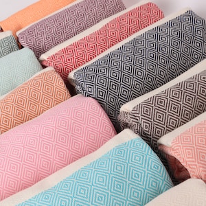 May include: A collection of colourful patterned throw pillows with a diamond pattern. The pillows are arranged in a row, with the colours ranging from orange to pink to blue.