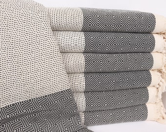 May include: A stack of six white and black patterned Turkish towels with fringe. The towels have a geometric diamond pattern.