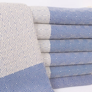 Könnte beinhalten: Ein Stapel aus sechs blauen und weißen türkischen Handtüchern mit Fransen. Die Handtücher haben ein geometrisches Muster und sind aus Baumwolle.