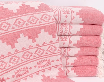 Puede incluir: Una pila de toallas de color rosa y blanco con bordes con flecos. Las toallas tienen un diseño geométrico.