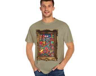 May include: A beige t-shirt with a gold framed print of a colorful collage of cartoon faces. The print features a variety of colors, including red, blue, green, and yellow.