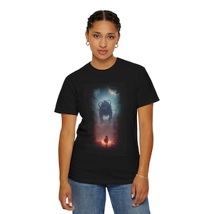 May include: A black t-shirt with a graphic print of a monster and a small figure walking towards it. The monster is blue and green, and the figure is red. The background is a dark forest.