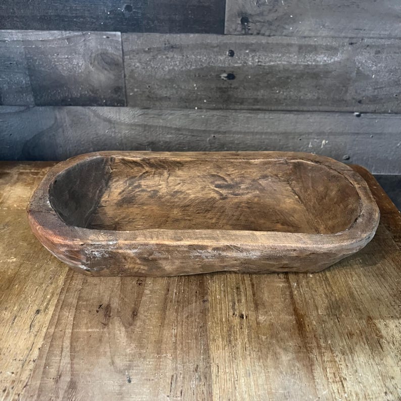 May include: A rustic wooden serving bowl with a natural brown finish. The bowl is oval shaped and has a slightly raised rim.
