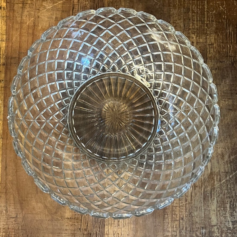May include: A clear glass bowl with a diamond pattern. The bowl is empty and has a reflective surface.