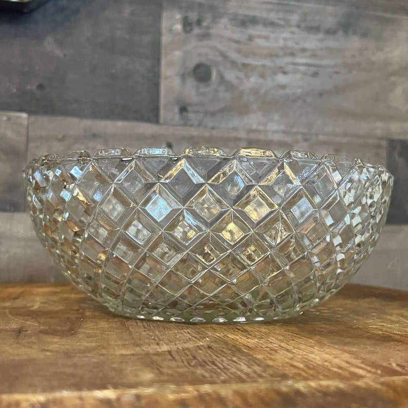 May include: A clear glass bowl with a diamond pattern. The bowl is oval shaped and has a slightly flared rim.