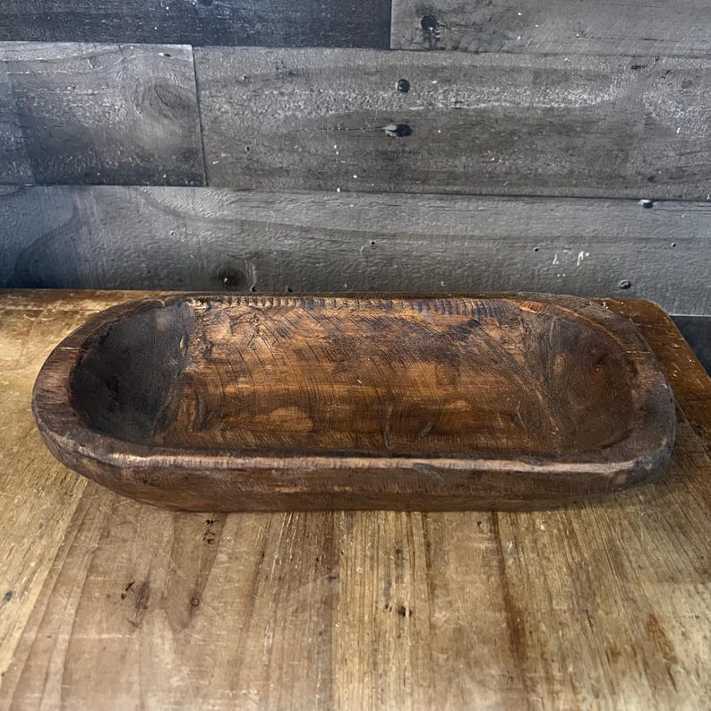 May include: A rustic wooden serving bowl with a natural brown finish. The bowl is oval shaped and has a slightly raised rim.