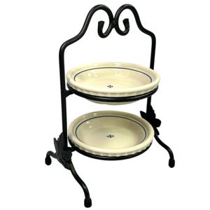 May include: A two-tiered stand featuring a black metal frame with decorative leaf accents at the base and a scroll-top handle. It holds two round, off-white ceramic bowls, each detailed with a thin blue circular rim and a small blue floral center.