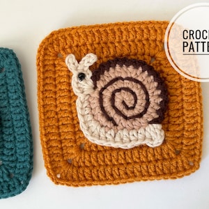Può includere: Un motivo quadrato all'uncinetto color giallo senape con un'applicazione a forma di lumaca con corpo beige chiaro e guscio a spirale nei toni del marrone e del beige. Il testo CROCHET PATTERN è visibile nell'angolo in alto a destra.