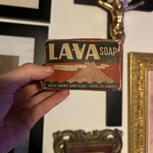 May include: A vintage box of Lava Soap, featuring a red and black design with the brand name and a mountain illustration. The box also includes the text "GETS GRIMY DIRT FAST - KIND TO HANDS".