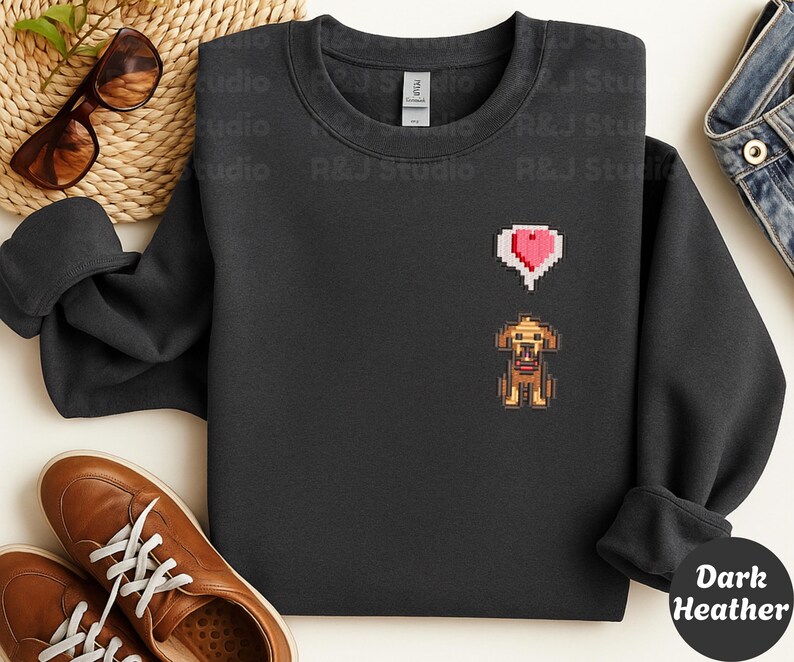 Dark Heather unisex crewneck sweatshirt showcasing a pixel art embroidered Stardew Valley dog with a red heart icon. The contrast stitching enhances the classic farming game aesthetic, making it a cozy gamer apparel choice for Stardew Valley fans, relaxed streetwear looks, indie game inspired outfits, and thoughtful gaming gifts.