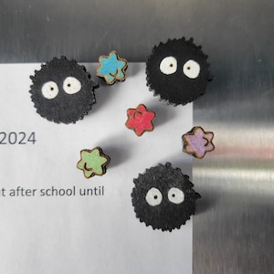 May include: Five wooden magnets, two black with white eyes, three star-shaped with different colors. The black magnets are fuzzy and resemble a character from the movie 'My Neighbor Totoro'. The text '2024' and 't after school until' are written on a white surface.