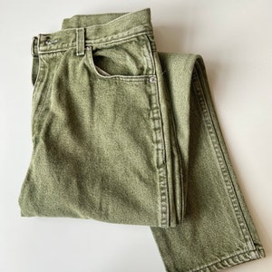 May include: A pair of green denim jeans folded in half. The jeans have a straight leg and a light wash.