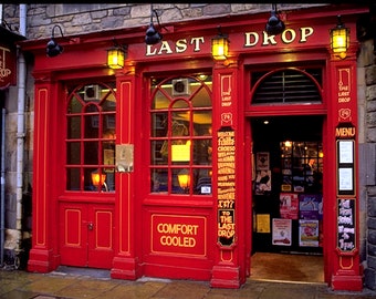 May include: A red brick building with a red door and windows. The building has a sign that says "The Last Drop" and a sign that says "Comfort Cooled".