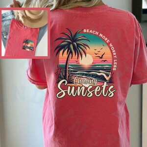 May include: Red t-shirt with a graphic of a palm tree and sunset on the back. The text "Beach More Worry Less" and "Chasing Sunsets" is printed on the shirt.
