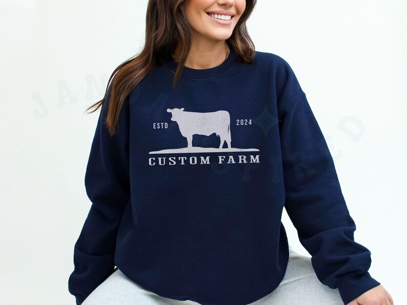 Puede incluir: Sudadera azul marino con una silueta blanca de una vaca y el texto "ESTD 2024 CUSTOM FARM".
