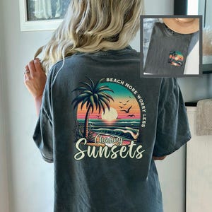 May include: A dark gray t-shirt with a sunset graphic and the text "Beach More Worry Less Chasing Sunsets".
