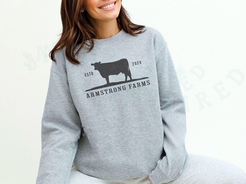 Puede incluir: Una sudadera gris con una silueta negra de una vaca y el texto "ESTD 2024 ARMSTRONG FARMS".