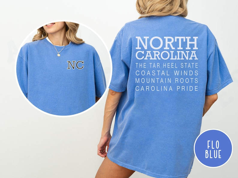 May include: Flo blue t-shirt with "NORTH CAROLINA" printed on the back, along with "THE TAR HEEL STATE", "COASTAL WINDS", "MOUNTAIN ROOTS", and "CAROLINA PRIDE". The front features "NC" in a collegiate style.