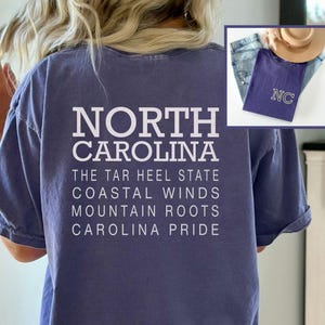 May include: A blue t-shirt with the words "NORTH CAROLINA" and other phrases printed in white. An inset image shows a similar shirt with "NC" embroidered on it, along with jeans and a hat. Clothing.