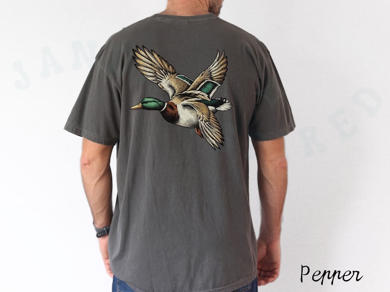 Może przedstawiać: Szary t-shirt z nadrukiem lecącego dzikiego kaczora na plecach.