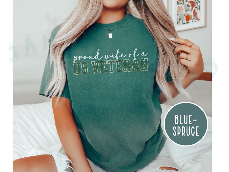 Puede incluir: Una camiseta de color verde azulado con el texto "proud wife of a US VETERAN" en letras blancas y verdes. La camiseta es de estilo casual y c&oacute;modo, perfecta para el uso diario. La camiseta est&aacute; etiquetada como "BLUE-SPRUCE".