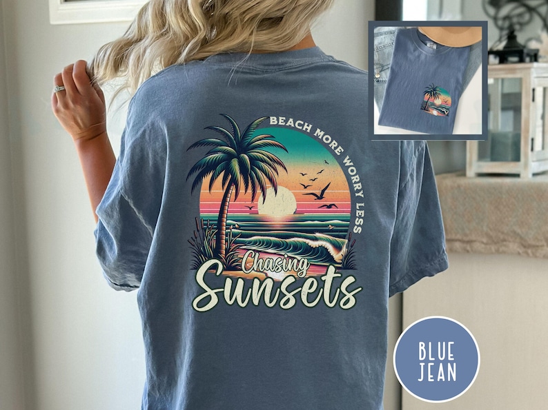 May include: A blue jean t-shirt with a graphic of a palm tree, sunset, and waves. The text "Beach More Worry Less" is written in a circle around the graphic. The text "Chasing Sunsets" is written below the graphic.