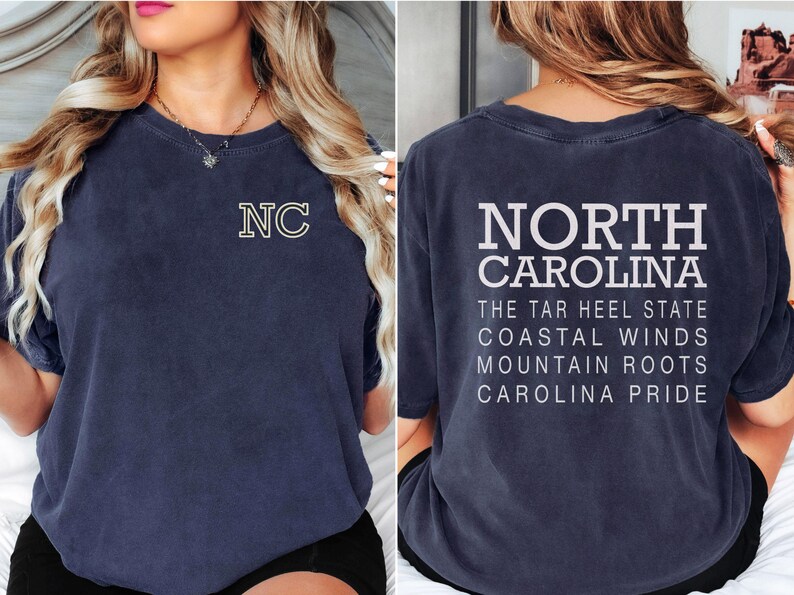May include: Navy blue t-shirt featuring "NC" with a yellow outline on the front. The back of the shirt displays "NORTH CAROLINA" in white block letters, along with state slogans. A casual, comfortable tee.