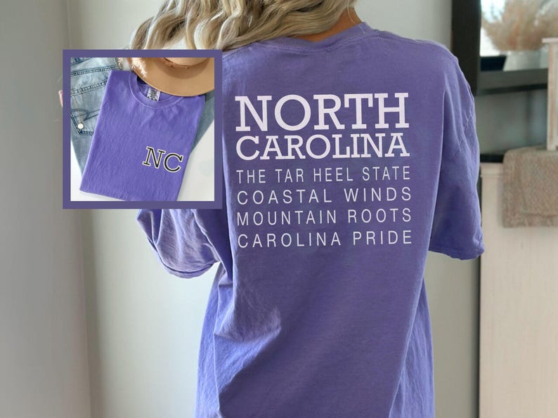 May include: A lilac t-shirt with the text "NORTH CAROLINA" and other phrases printed in white. An inset shows a matching shirt with "NC" embroidered. The shirt is a casual wear item.