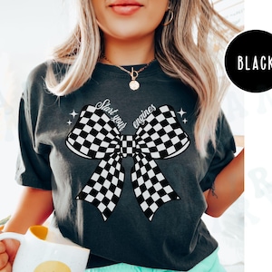 May include: A dark gray t-shirt with a black and white checkered bow and the text "Start your engines" printed on the front.